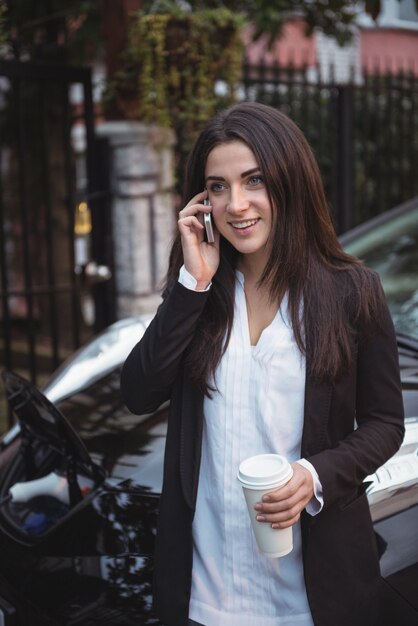 Woman talking on mobile phone while car being charged