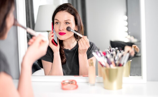 Woman talking on phone and doing make up