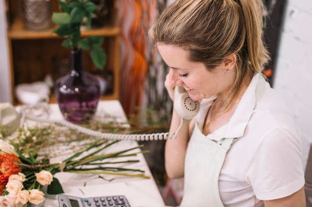 Free photo woman talking on phone in floral shop