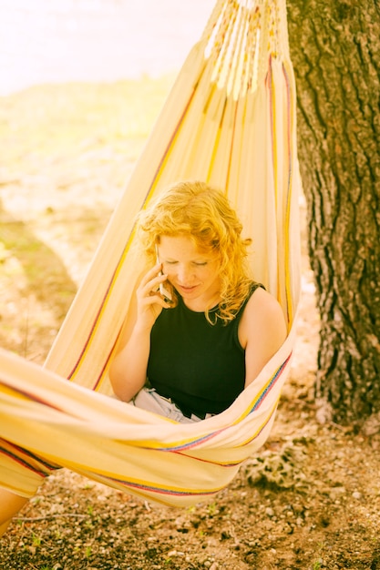 Free photo woman talking on phone in hammock