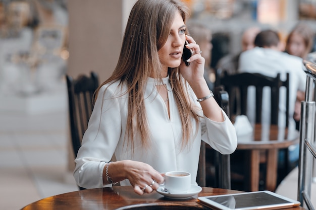 Woman talking on the phone and holding a cup of coffee