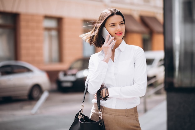 Free Photo woman talking on the phone outside the city streets