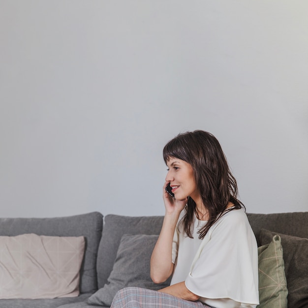 Woman talking on phone sitting on couch