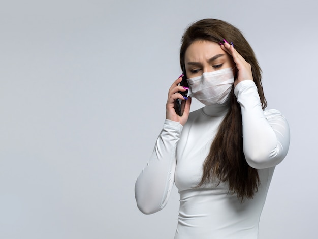 Woman talking on the phone, suffering from headache and holding her head