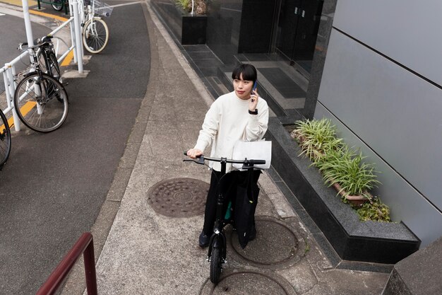 Woman talking on the phone and using electric bicycle in the city