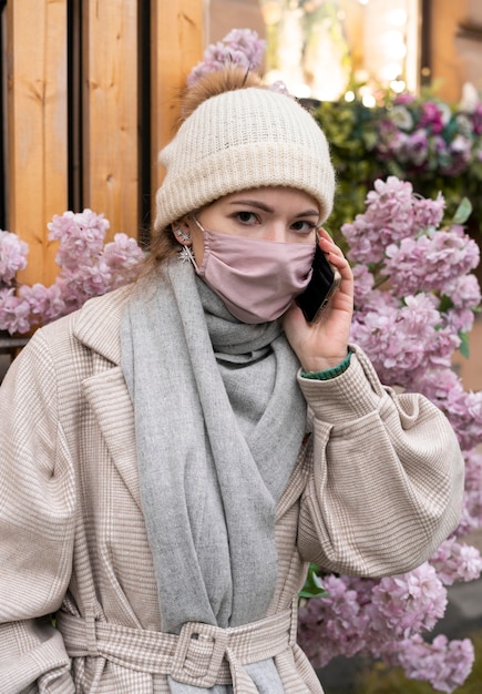 Free Photo woman talking on the phone while wearing medical mask