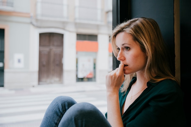 Free photo woman thinking near cafe window