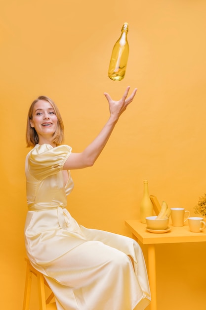 Free photo woman throwing bottle in air in a yellow scene