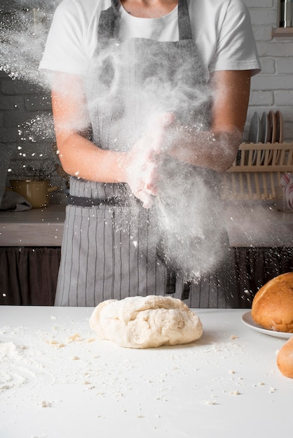 Woman throwing flour over dough