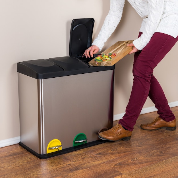 Free photo woman throwing the wasted food into the steel bin