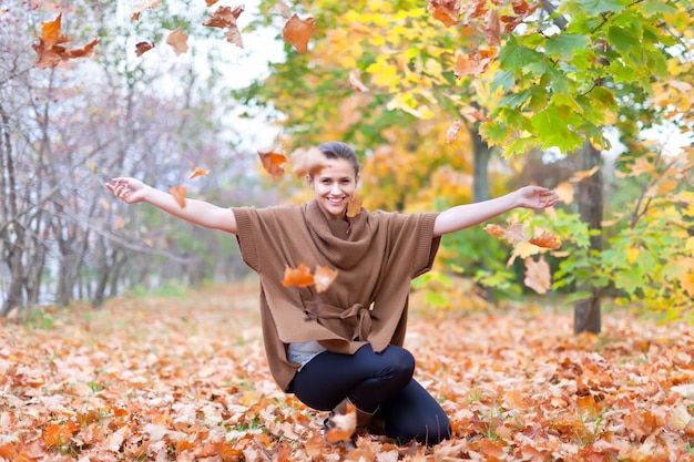 Free photo woman throws autumn leaves