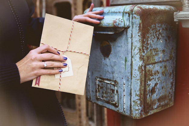 Free photo woman throws an envelope of santa claus in an old vintage mail box