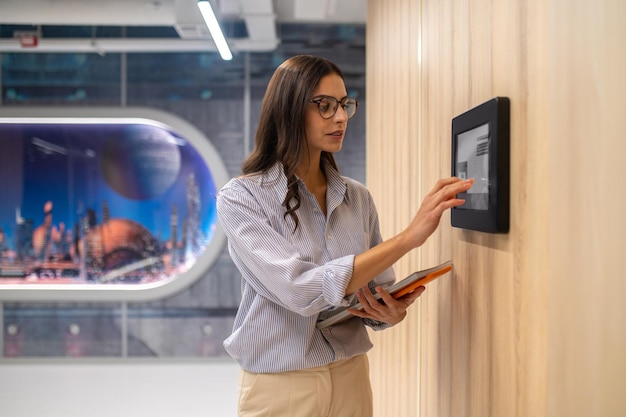 Woman touching control panel on wall in corridor