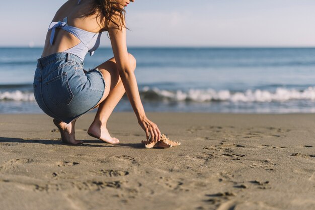 Woman touching starfish at the beach