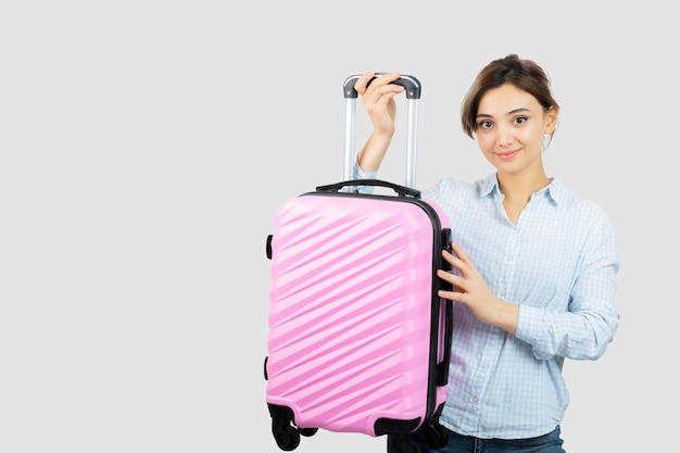 Woman tourist standing and holding pink travel suitcase . High quality photo