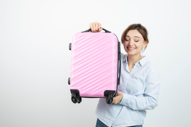 Woman tourist standing and holding pink travel suitcase . High quality photo