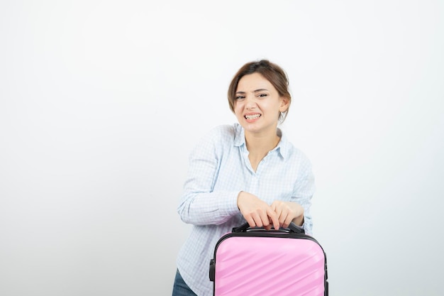 Woman tourist standing and holding pink travel suitcase . High quality photo