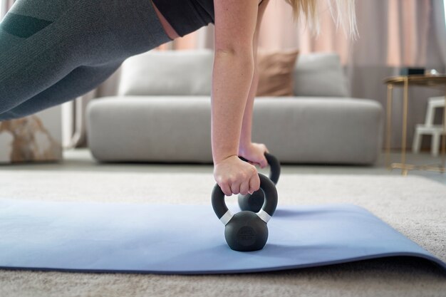 Woman training with kettlebell on mat