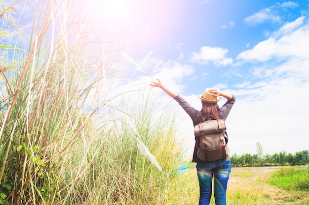 woman traveler push hands and breathing at field of grasses and blue sky, wanderlust travel concept, space for text