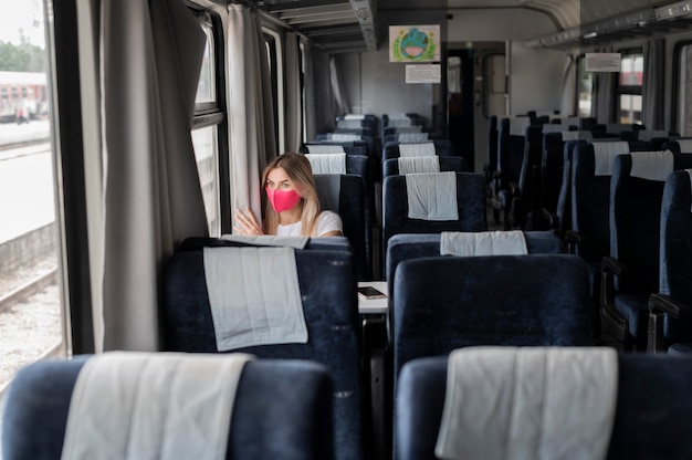 Free photo woman traveling by train and wearing medical mask for protection