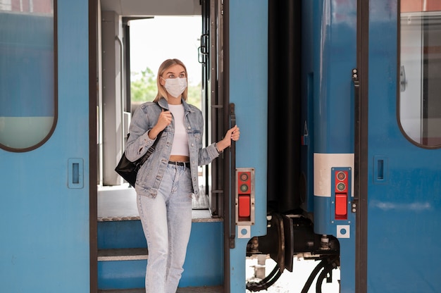 Free photo woman traveling by train wearing medical mask for protection