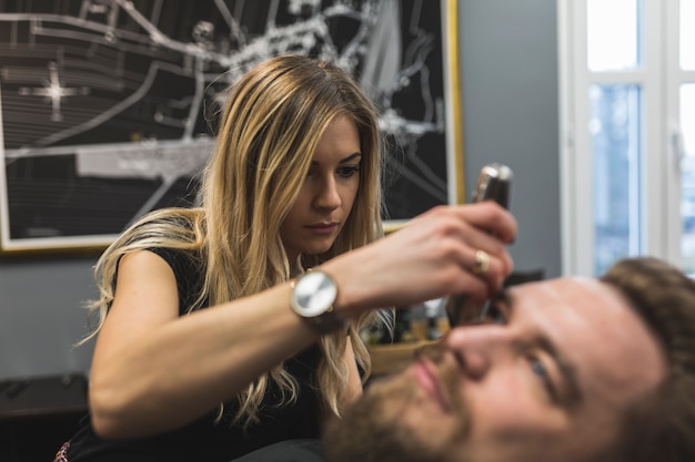 Free photo woman trimming beard of client