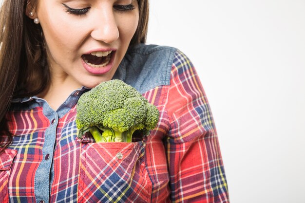 Woman trying to bite broccoli in pocket