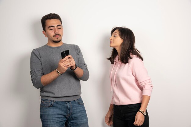 Woman trying to look into his phone on white.