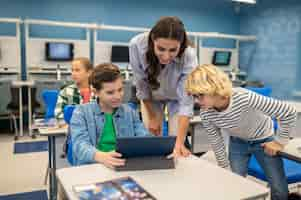 Free photo woman and two students looking at tablet