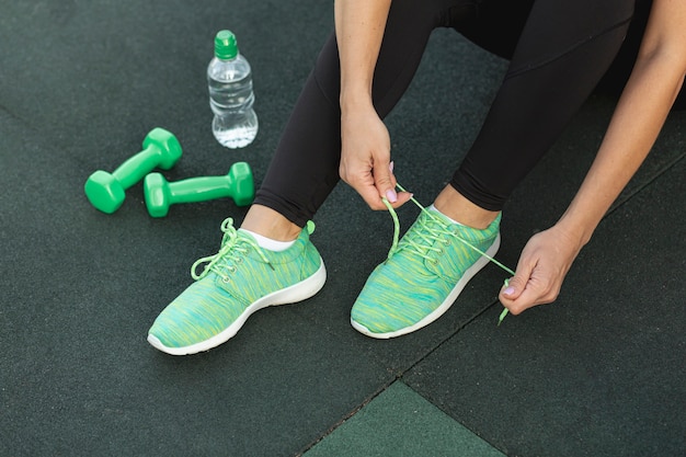 Free photo woman tying her green sneakers