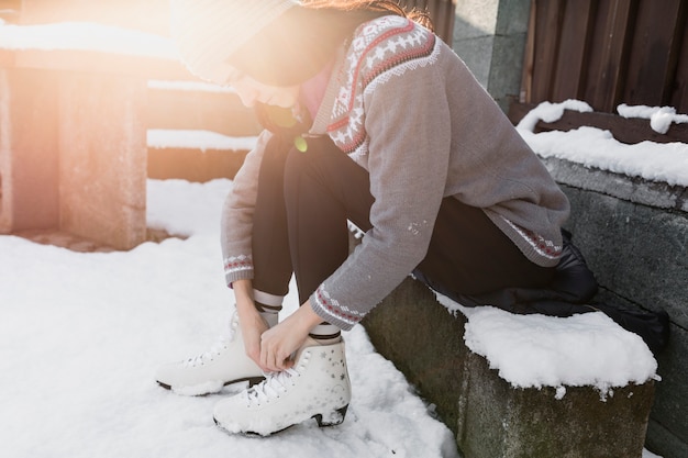 Free photo woman tying skates on bench