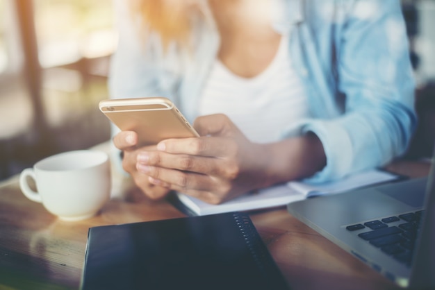 Woman typing on her phone with a cup