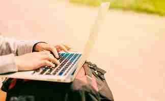 Free photo woman typing on laptop placed on backpacks