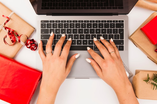 Free Photo woman typing on laptop with christmas boxes on table