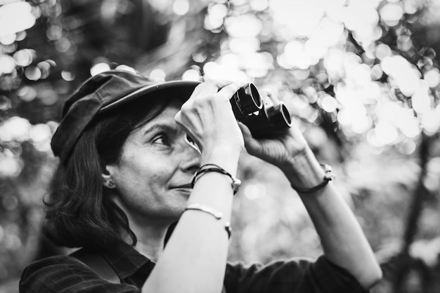 Free photo woman using binoculars in the forest