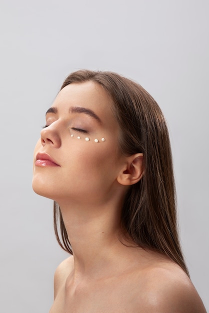 Woman using eye cream side view