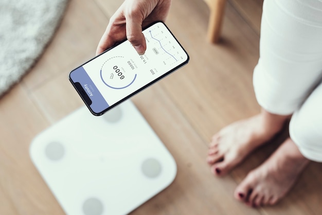 Free Photo woman using health tracking on her phone by the weighing scale  innovative technology