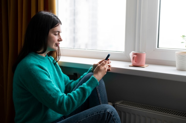 Free photo woman using her smartphone at home during quarantine