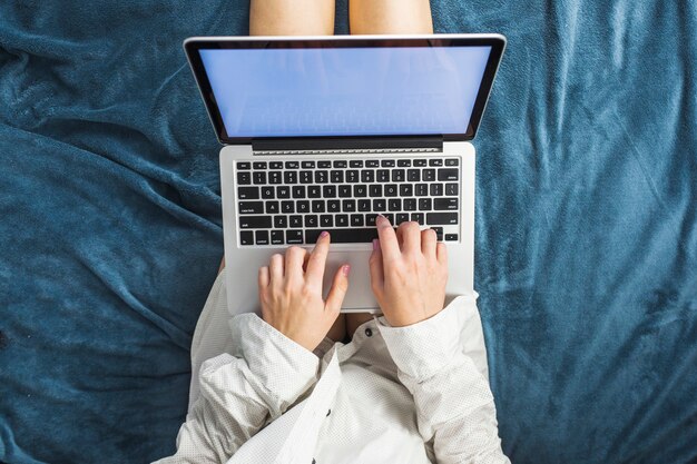 Woman using laptop on bed 