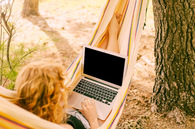 Free photo woman using laptop in hammock