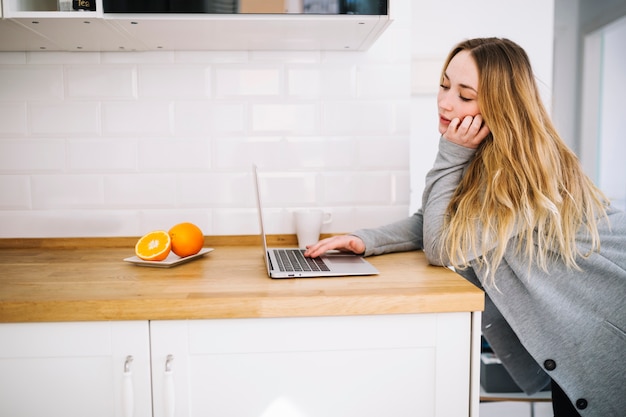 Free photo woman using laptop on kitchen