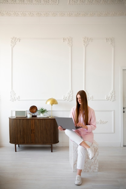 Free photo woman using laptop in minimal decorated room