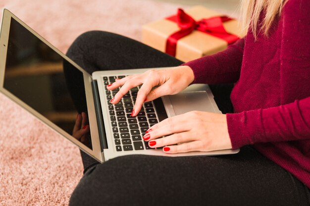 Woman using laptop near gift box