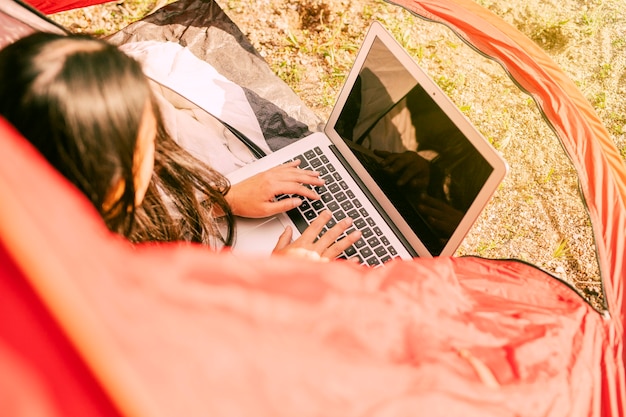 Free photo woman using laptop while resting in camping