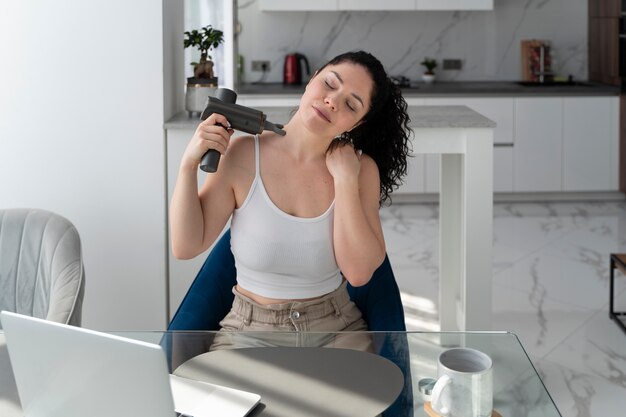 Woman using massage gun high angle