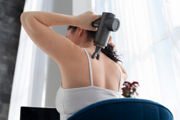 Woman using massage gun low angle