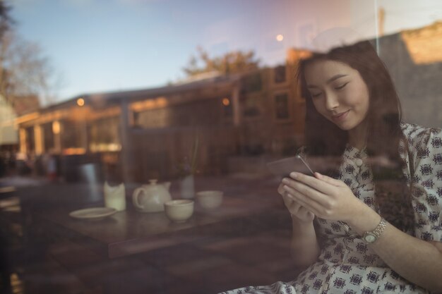 Woman using mobile phone near window