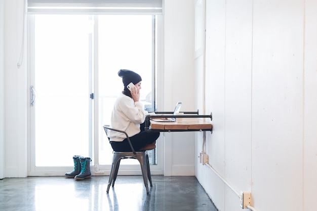 Free photo woman using phone and laptop in office