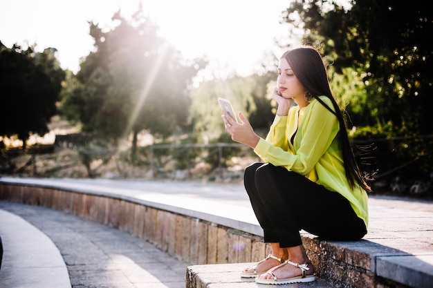 Woman using phone in sunny park