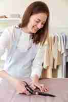 Free photo woman using scissors to cut fabric